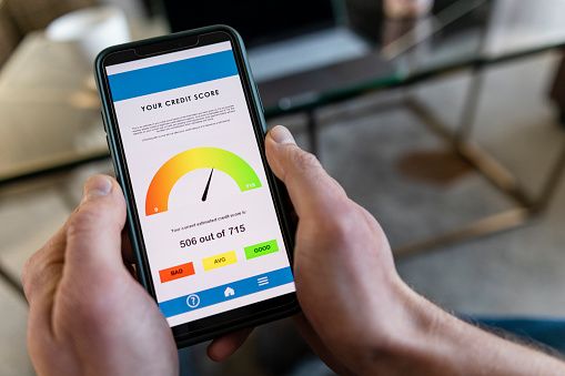 Person checking their credit score on a smartphone, displaying a score of 506 labeled as “Average,” during a free credit score check at home.