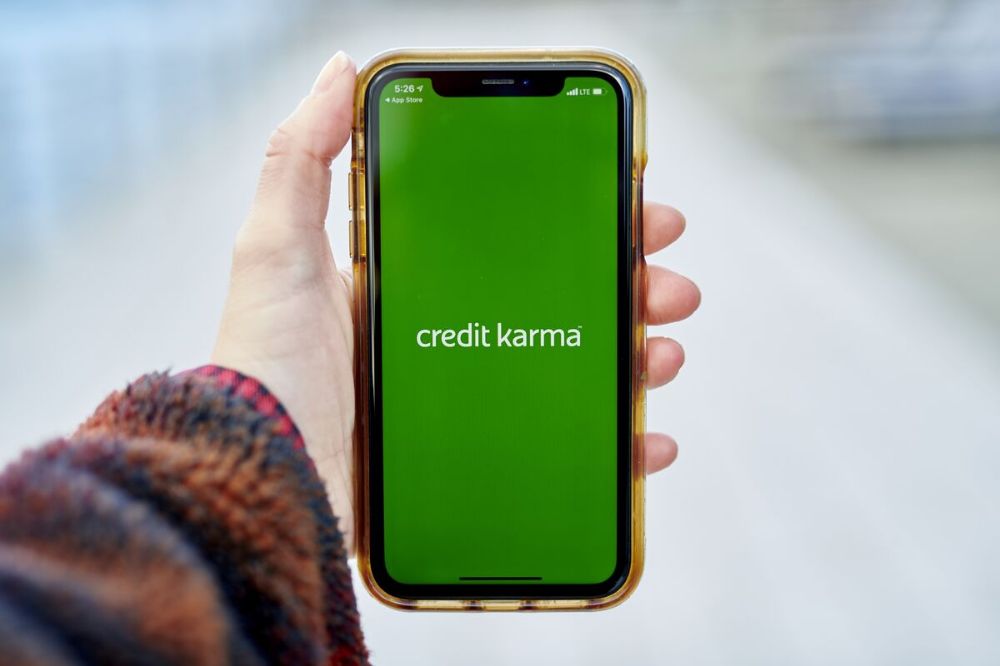 Person holding a smartphone showing the Credit Karma app loading screen, a popular platform for performing a free credit score check in 2025.