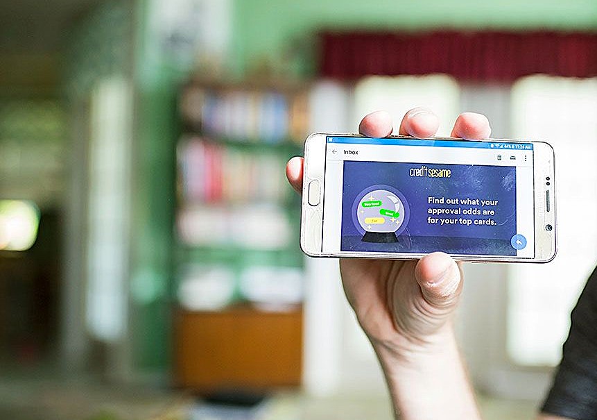 Person holding a smartphone displaying the Credit Sesame app screen, a trusted platform for performing a free credit score check and tracking credit card approval odds.